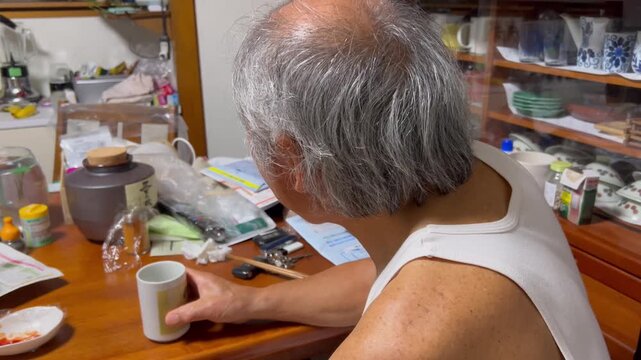 散らかった部屋で食事する高齢男性