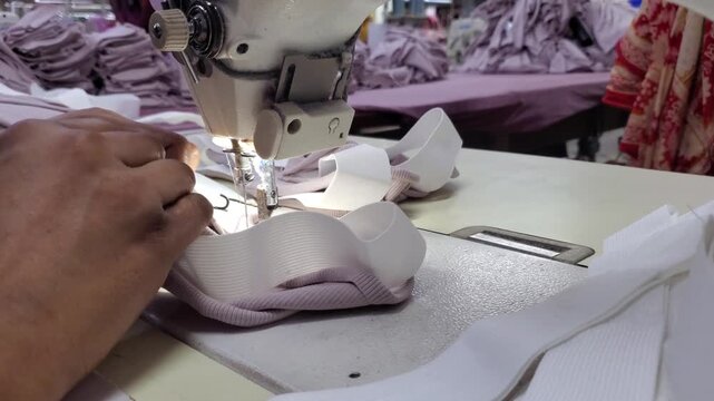 Close up of sewing machine stitching elastic band in garment factory,.
textile industry worker sewing elastic waistband
