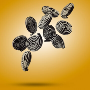 Liquorice candy wheels flying on yellow background.