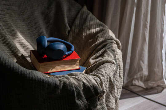 Cozy armchair with books and headphones, ready for relaxing, reading, or listening to music and podcasts in sunlight
