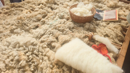 Natural sheep wool is prepared by hand for traditional spinning and textile crafts. Concepts: wool processing, traditional craft, fiber production, cultural heritage, handmade textiles. © Sana Baleia