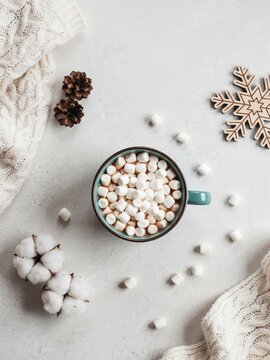 Overhead view of a teal mug filled with mini marshmallows and hot chocolate surrounded by winter themed decorations