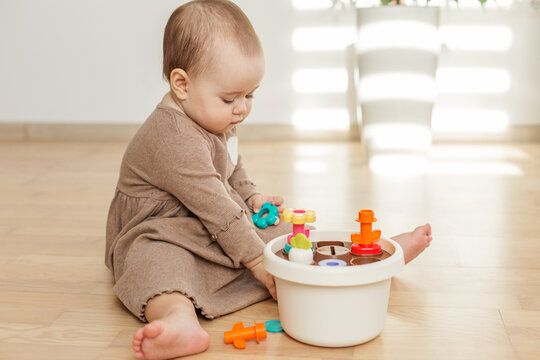 Baby playing with colorful shape sorter toy on floor