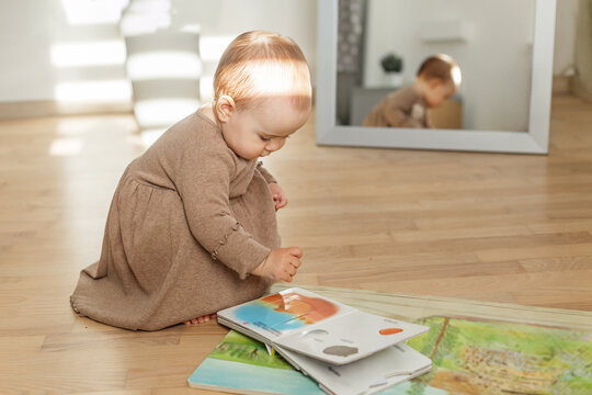 Baby looking at picture book on wooden floor