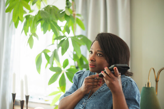 Mature woman listening to voicemail through smart phone at home