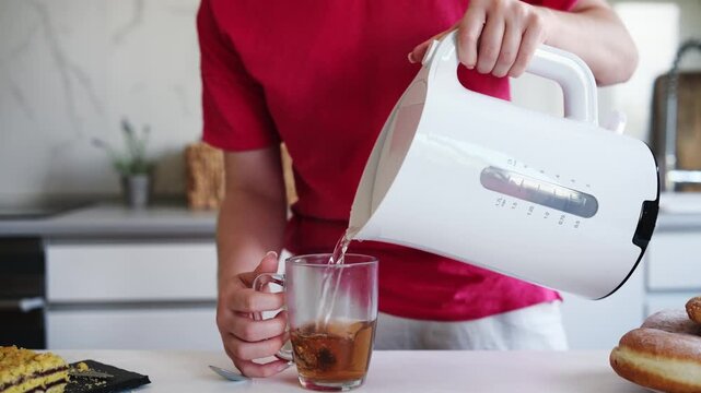 Girl Pouring Boiling Water Into Cup From Kettle To Prepare Tea