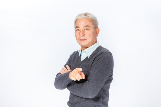 Portrait of serious senior Asian man with arms crossed on white background
