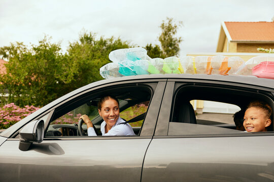 Smiling woman driving car with family while going for weekend trip