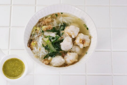 Top View of Traditional Indonesian wajik rice cakes made from glutinous rice and palm sugar are arranged on a white plate with pandan leaves and served with a cup of tea.