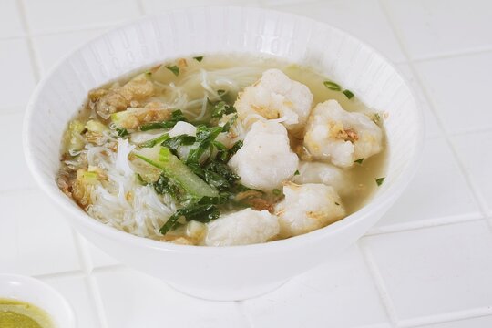 Traditional Indonesian tekwan soup with fish balls, noodles and fresh herbs served in a white bowl, highlighting the comforting appearance of this Palembang specialty.