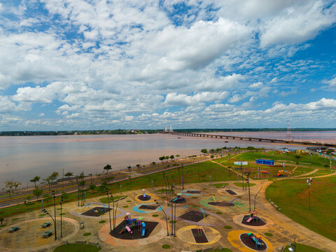 Aerial view of the waterfront park with playground equipment and the San Roque Gonzalez de Santa Cruz bridge spanning the Parana River in Posadas, Misiones Province, Argentina.