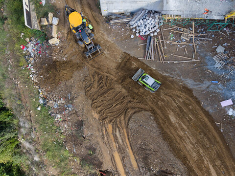 Aerial view of a construction site with a yellow backhoe loader and a small green roller on muddy ground in Istanbul, Istanbul, Turkiye.