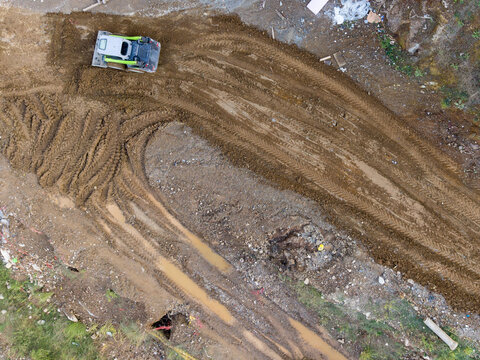Aerial view of a skid steer loader working on a muddy construction site with deep tire tracks in Istanbul, Istanbul, Turkiye.