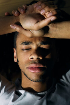 Directly above shot of young man resting while lying on floor with serious expression