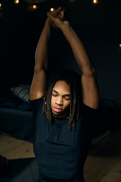 Young man stretching his arms while doing yoga at home
