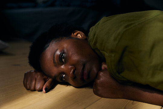 Anxious woman contemplating while lying on floor at home