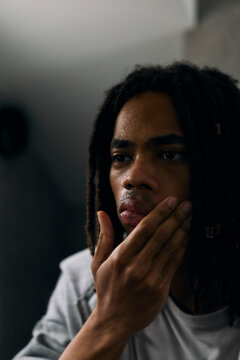 Stressed young man touching his face while looking in mirror at home