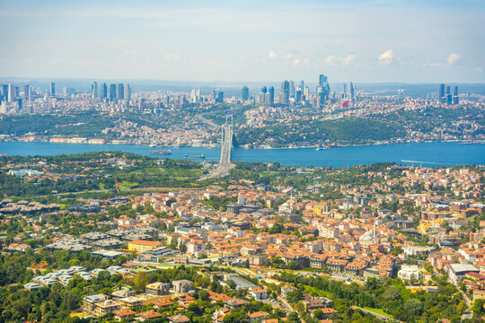 Aerial view of Istanbul cityscape featuring Bosphorus Bridge, modern skyscrapers, and lush greenery along the waterfront