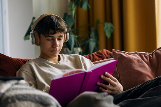 Teenage boy listening to music while writing in diary at home