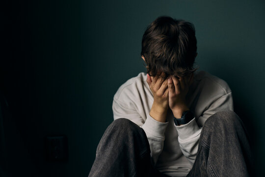 Upset boy crying while sitting against wall