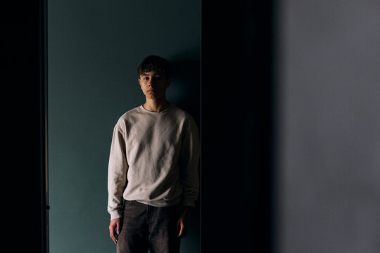 Portrait of worried teenage boy standing against wall