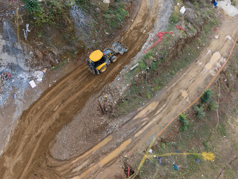 Aerial view of a yellow construction loader working on a muddy dirt road at a development site in Istanbul, Istanbul, Turkiye.