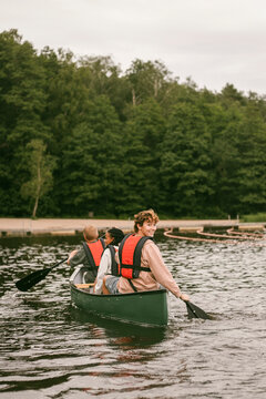 Female camp counselor looking over shoulder during boating activity with children