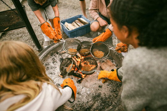 High angle view of children cooking popcorn over fire at summer camp