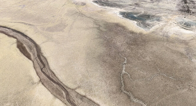 Aerial view of a completely dry riverbed with cracked earth and parched channels cutting through the arid landscape, highlighting severe drought in Bloemhof, North West, South Africa.