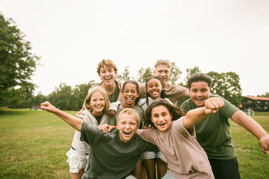 Portrait of cheerful friends and their group leaders posing for fun team photo at summer camp