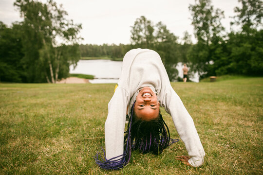 Portrait of girl with braided hair doing backbend bridge stretch on grass at park