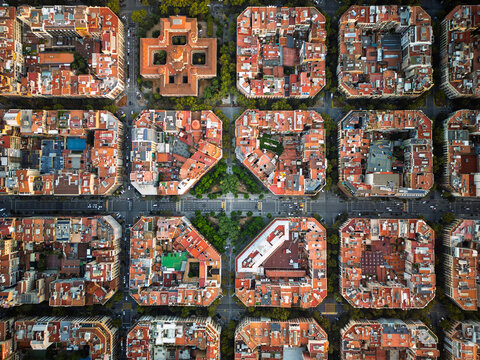Aerial view of the iconic octagonal city blocks and grid layout of the Eixample district with red rooftops and inner courtyards in Barcelona, Catalonia, Spain.