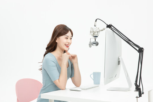Smiling female streamer chatting with viewers during a live online broadcast at a computer
