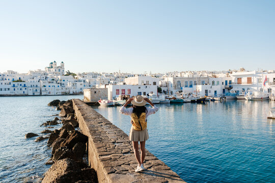 Strolling along the picturesque harbor of Naousa, Paros, Greece under a clear blue sky