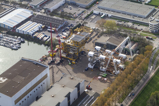Aerial view of Rotterdam Harbour featuring industrial infrastructure, large cranes, and heavy machinery at the port facility in Rotterdam, South Holland, Netherlands.