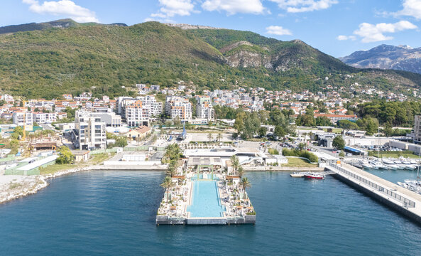Aerial view of the Lido Mar infinity pool at Porto Montenegro marina, surrounded by luxury yachts, coastal buildings, and mountains in Tivat, Tivat Municipality, Montenegro.