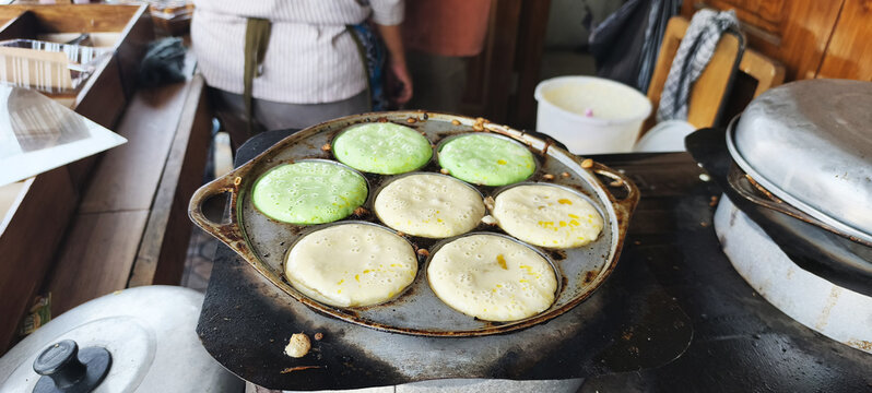 The process of making *Apem* cakes: frying and flipping the cakes in the pan. *Apem* is a traditional Javanese snack made from rice flour.

