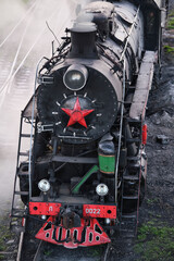 Moscow, Russia - September 30, 2026: Steam locomotives from USSR  with red star stands and smoke from the steam locomotive's chimney on the railroad tracks in the museum exposition. Retro steam train. © VLAD ANTONOV