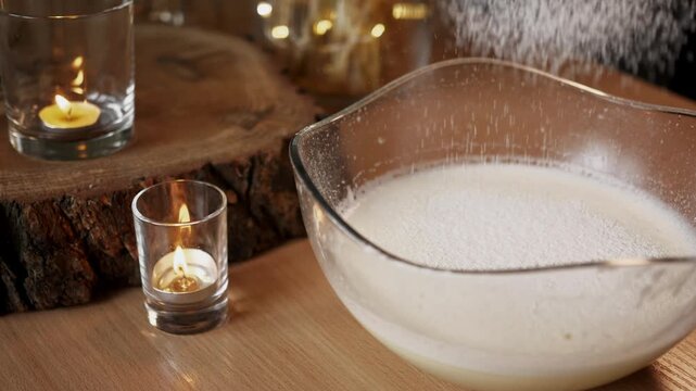 Sifting white flour through sieve into whipped egg mixture in glass bowl