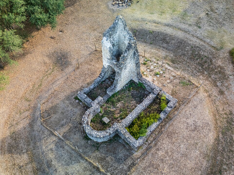 Aerial view of the medieval Csabdi church ruins, with weathered stone walls, an arched sanctuary and overgrown foundations in a dry rural clearing in Hungary.