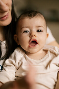 Baby smiles wide while held close by loving parent in soft warm home light