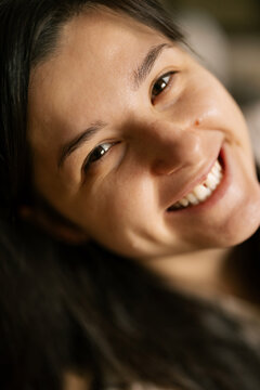Happy woman smiles warmly while lying down in soft natural light