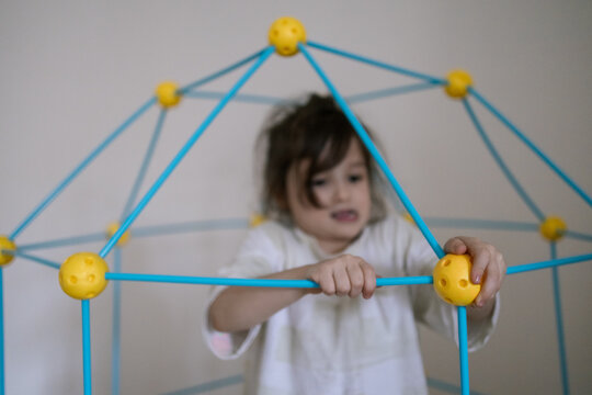Little child plays with colorful plastic toy structure in bright room showing joyful learning moment