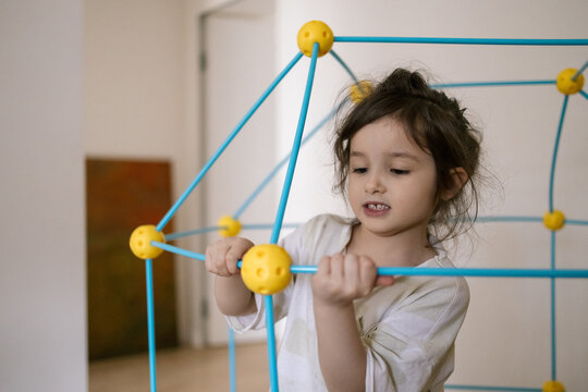 Young girl plays with colorful building toy indoors focused and engaged in creative play