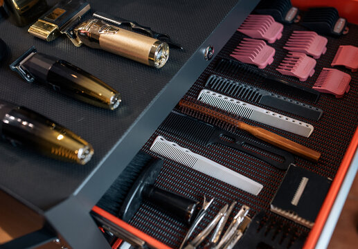 Professional barber tools and hair clippers arranged in a grooming case. The organized equipment represents professional hairstyling, barbering and modern men's grooming.