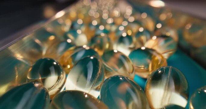 Slow motion closeup of softgel capsules sliding along blue conveyor belt in pharmaceutical production line inside factory.
