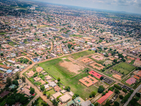 Aerial view of Barnawa district in Kaduna featuring residential houses, a large open field, and institutional buildings under a cloudy sky in Kaduna, Kaduna, Nigeria.