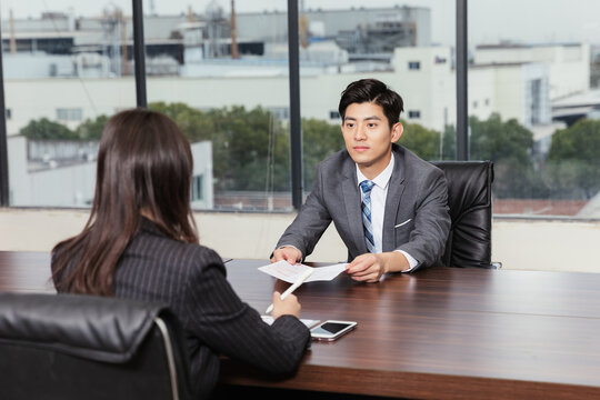Young businessman interviewing female candidate in modern office