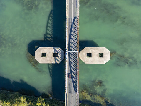 Aerial view of Ura e re e Buna bridge crossing the turquoise waters of the Buna river with concrete supports and a car driving across in Shkoder, Qarku i Shkodres, Albania.