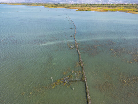 Aerial view of Shkodra Lake featuring a traditional fishing structure extending into the clear water with distant shoreline in Shiroka, Shkoder County, Albania.